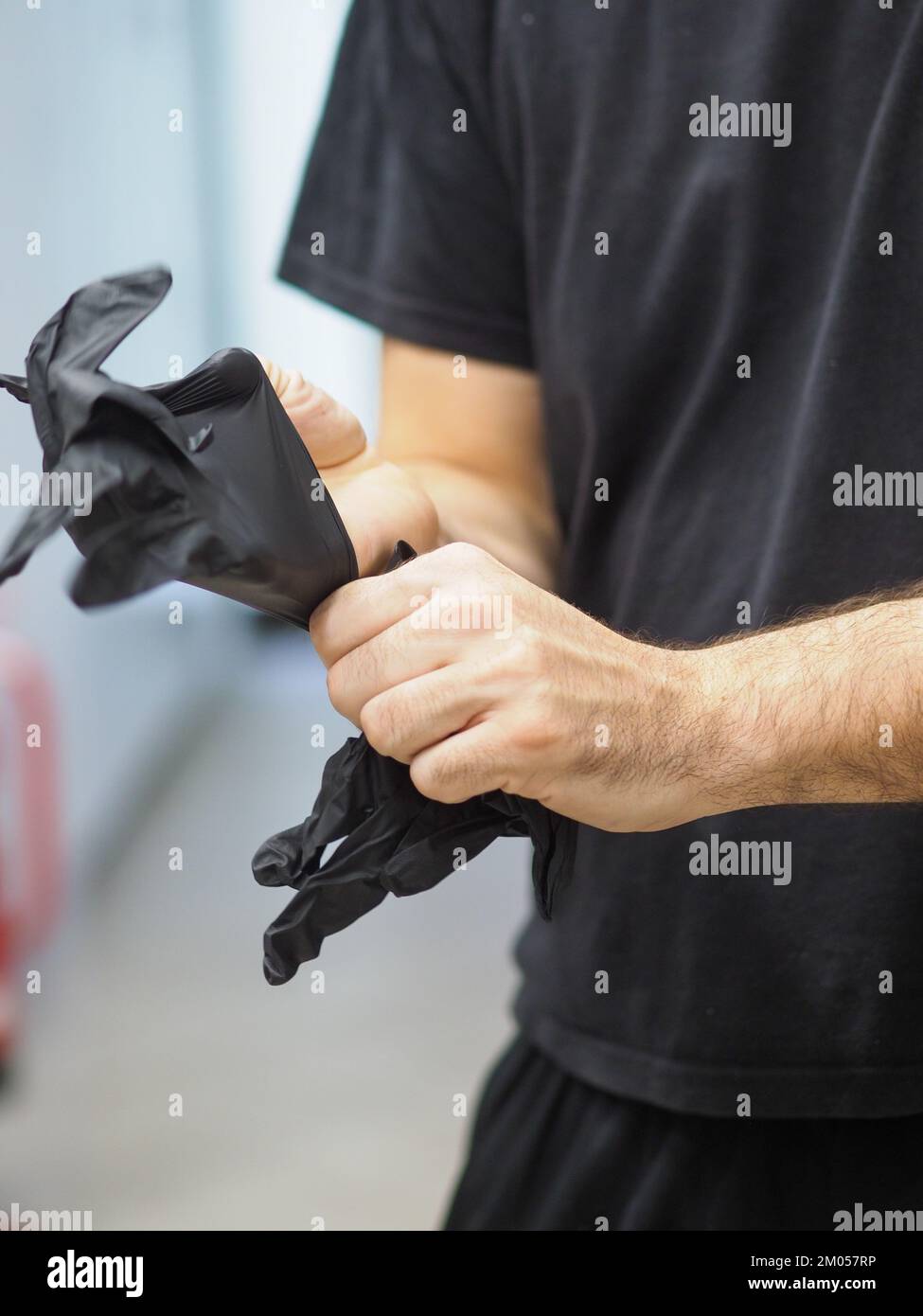 lo chef indossa guanti neri in una cucina professionale prima di cucinare filmati verticali Foto Stock