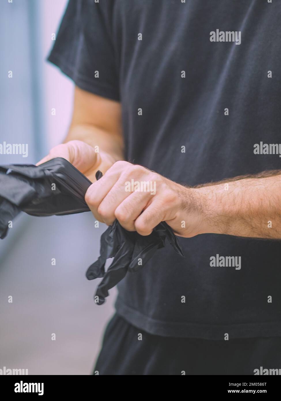 lo chef indossa guanti neri in una cucina professionale prima di cucinare filmati verticali Foto Stock