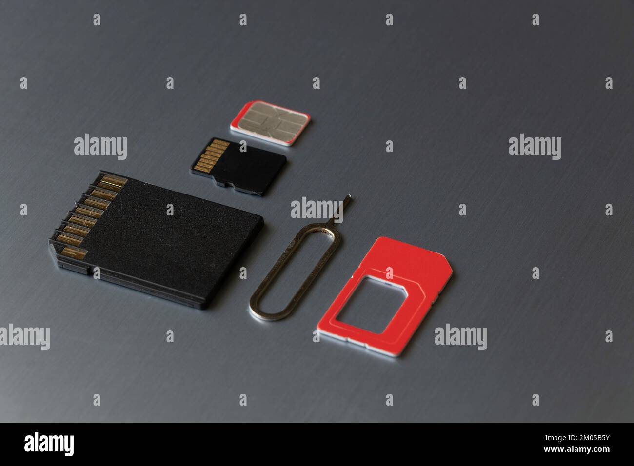 La scheda SIM e la graffetta per aprire lo slot della scheda SIM e la scheda di memoria si trovano su uno sfondo grigio in acciaio Foto Stock
