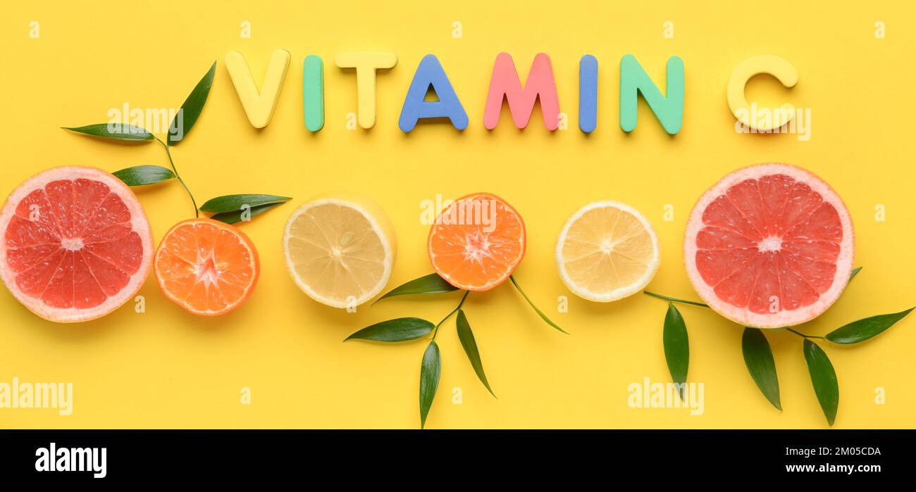 Testo VITAMINA C e agrumi tagliati su sfondo giallo Foto Stock