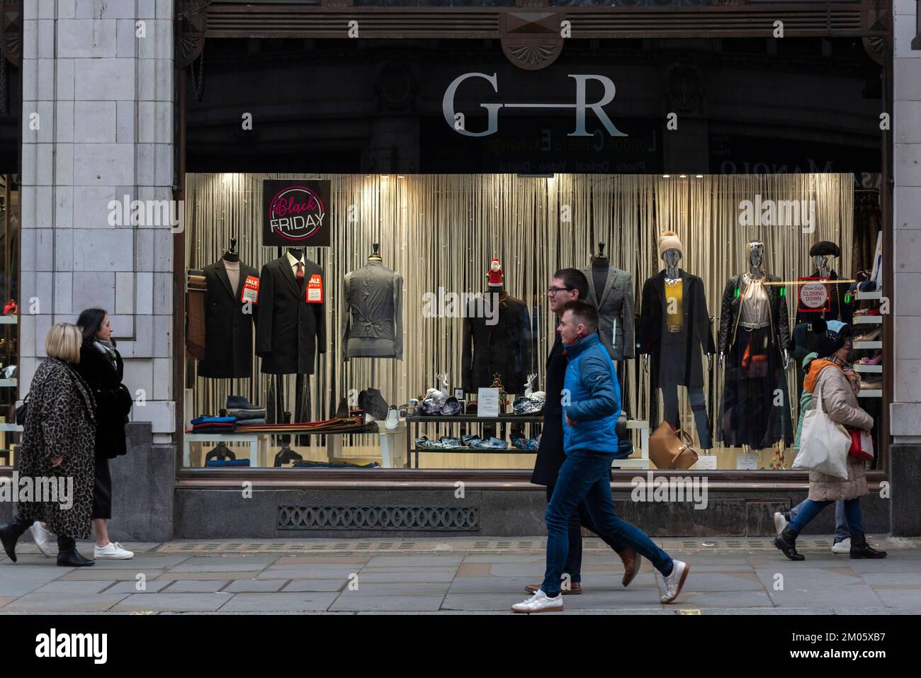 Vendita Black Friday vicino a Natale in vetrina Gee Ricci a The Strand, Londra, Regno Unito. Negozio di moda maschile Foto Stock