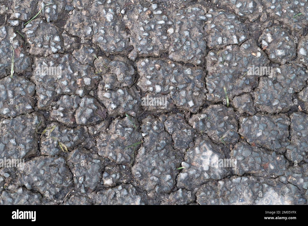 Gelo / fatica danneggiato superficie di asfalto con scricchiolio di alligatore su una strada rurale / di campagna nel Regno Unito. Per la manutenzione di strade malfunzionante, vecchio asfalto, Foto Stock