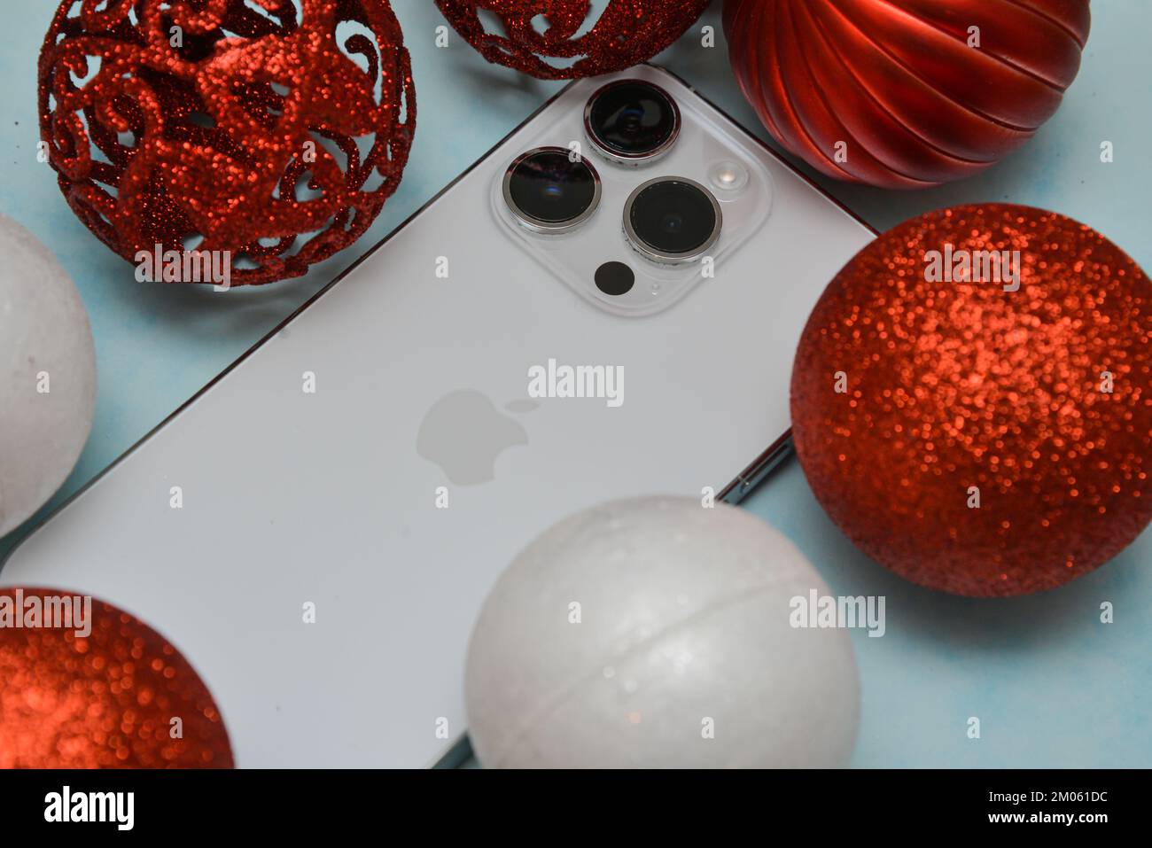 Riga/Lettonia - 4 dicembre 2022: Nuovo telefono moderno iPhone 14 pro tra le scintillanti decorazioni natalizie su sfondo nero. Regalo di Natale conce Foto Stock