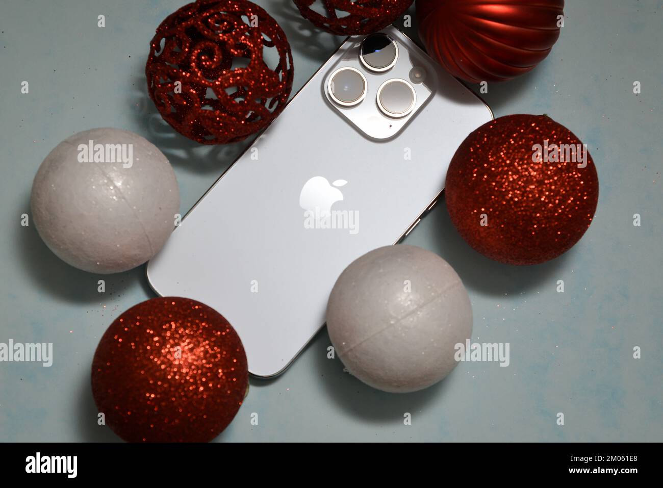 Riga/Lettonia - 4 dicembre 2022: Nuovo telefono moderno iPhone 14 pro tra le scintillanti decorazioni natalizie su sfondo nero. Regalo di Natale conce Foto Stock