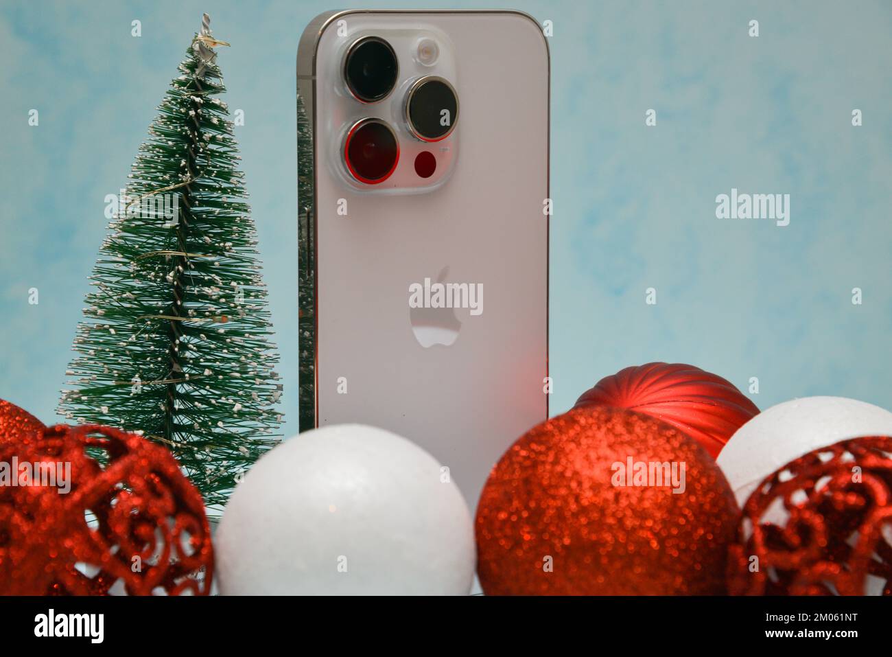 Riga/Lettonia - 4 dicembre 2022: Nuovo telefono moderno iPhone 14 pro tra le scintillanti decorazioni natalizie su sfondo nero. Regalo di Natale conce Foto Stock
