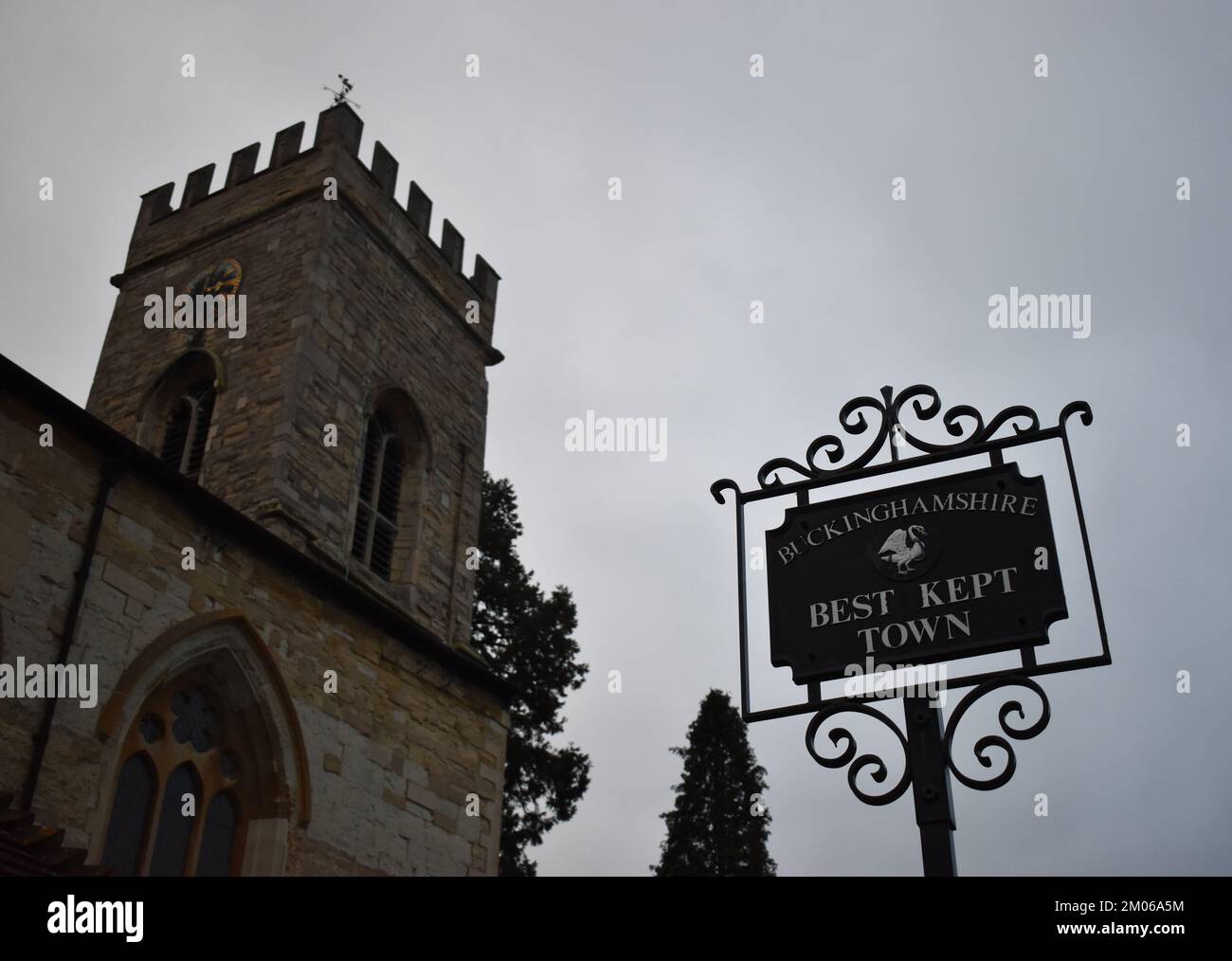 Cartello "Città meglio tenuta" a Stony Stratford, Milton Keynes con sullo sfondo la chiesa di St Mary e St Giles. Foto Stock