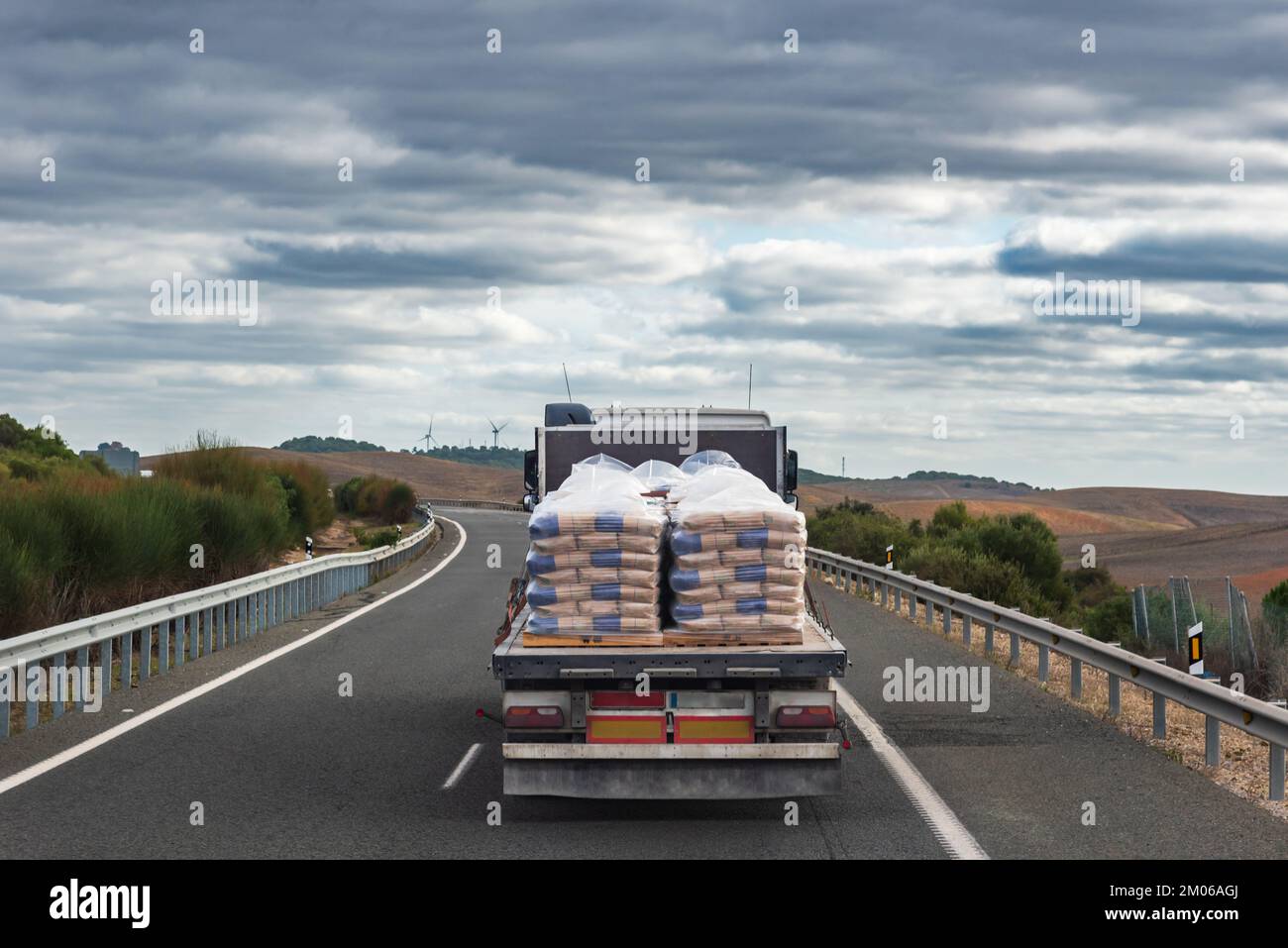 Autocarro carico di sacchi di cemento guida su strada. Foto Stock