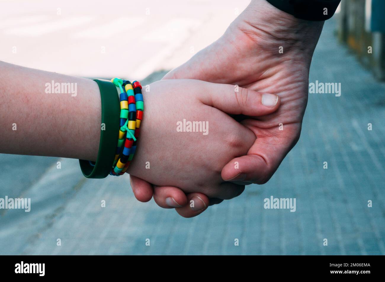 Una mano della madre e una mano del figlio insieme, camminando giù la strada. Foto Stock