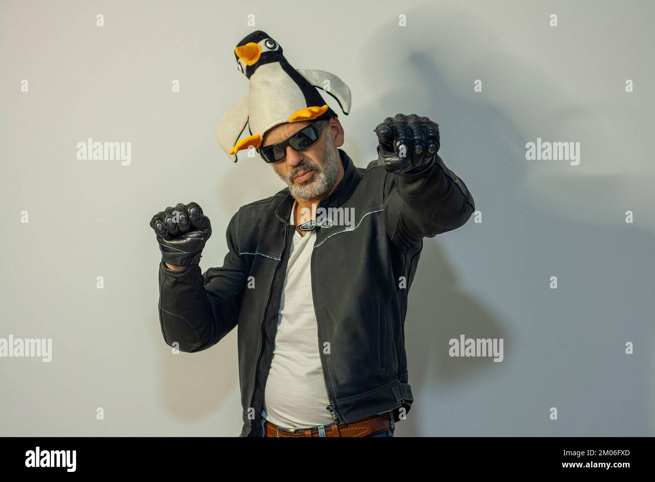 uomo vestito da motociclista con giacca e guanti in pelle con cappello di pinguino pronto per andare alla concentrazione invernale di pinguini a valladolid Foto Stock