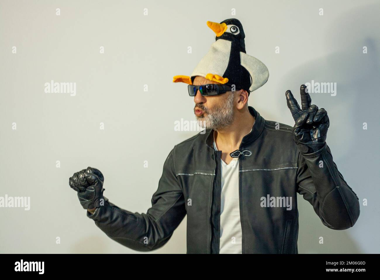 uomo vestito da motociclista con giacca e guanti in pelle con cappello di pinguino pronto per andare alla concentrazione invernale di pinguini a valladolid Foto Stock