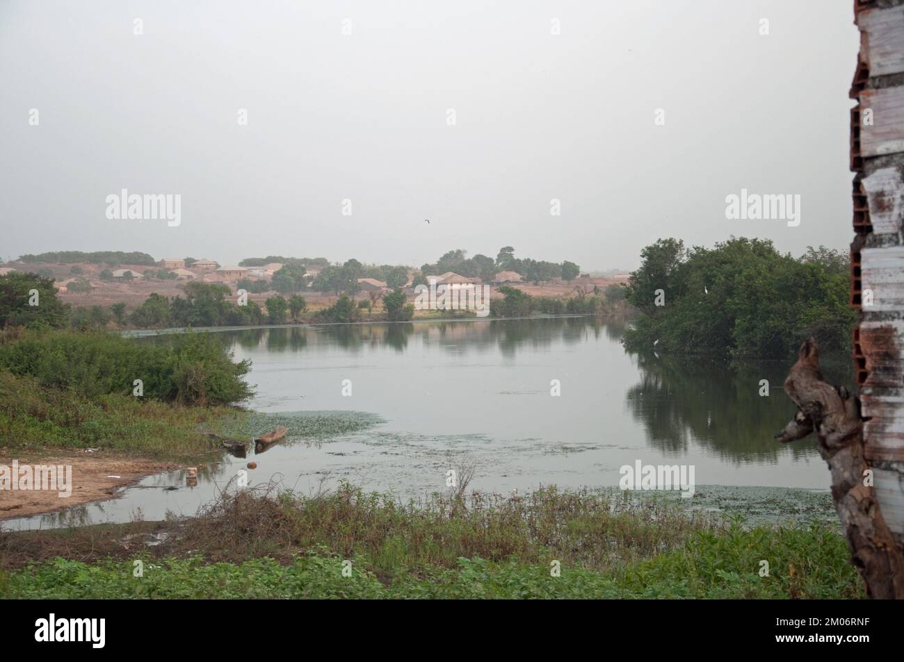 Fiume Geba, Bafata, Bafata Regione, Guinea Bissau. Grande fiume, molto fermo o in movimento lentamente, Case sulla riva lontana, vegetazione Foto Stock