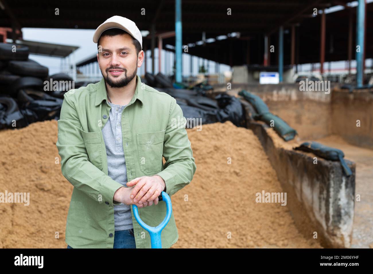 Contadino in piedi in fattoria all'aperto vicino al mucchio di bagasse di birra Foto Stock