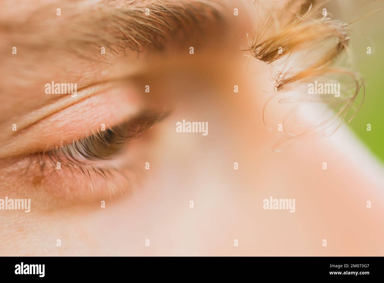 occhio maschio da vicino. un ricciolo di capelli ricci pende sul viso di un uomo. uno sguardo attento nel vuoto. Foto Stock