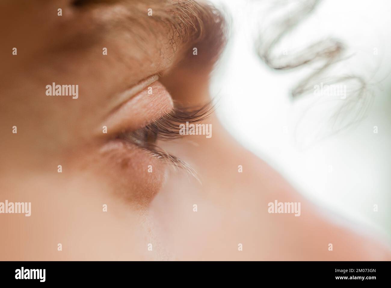 occhio maschio da vicino. un ricciolo di capelli ricci pende sul viso di un uomo. uno sguardo attento nel vuoto. Foto Stock