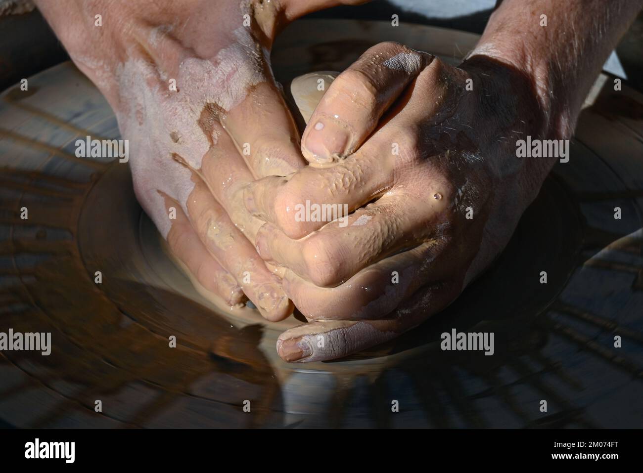 Un primo piano di due mani bagnate che formano un cono di argilla in una ciotola su una ruota di ceramica in una dimostrazione alla fiera d'arte di Tucson, Arizona Foto Stock