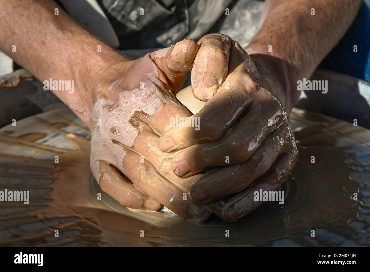 Un primo piano di due mani bagnate che formano un cono di argilla in una ciotola su una ruota di ceramica in una dimostrazione alla fiera d'arte di Tucson, Arizona Foto Stock