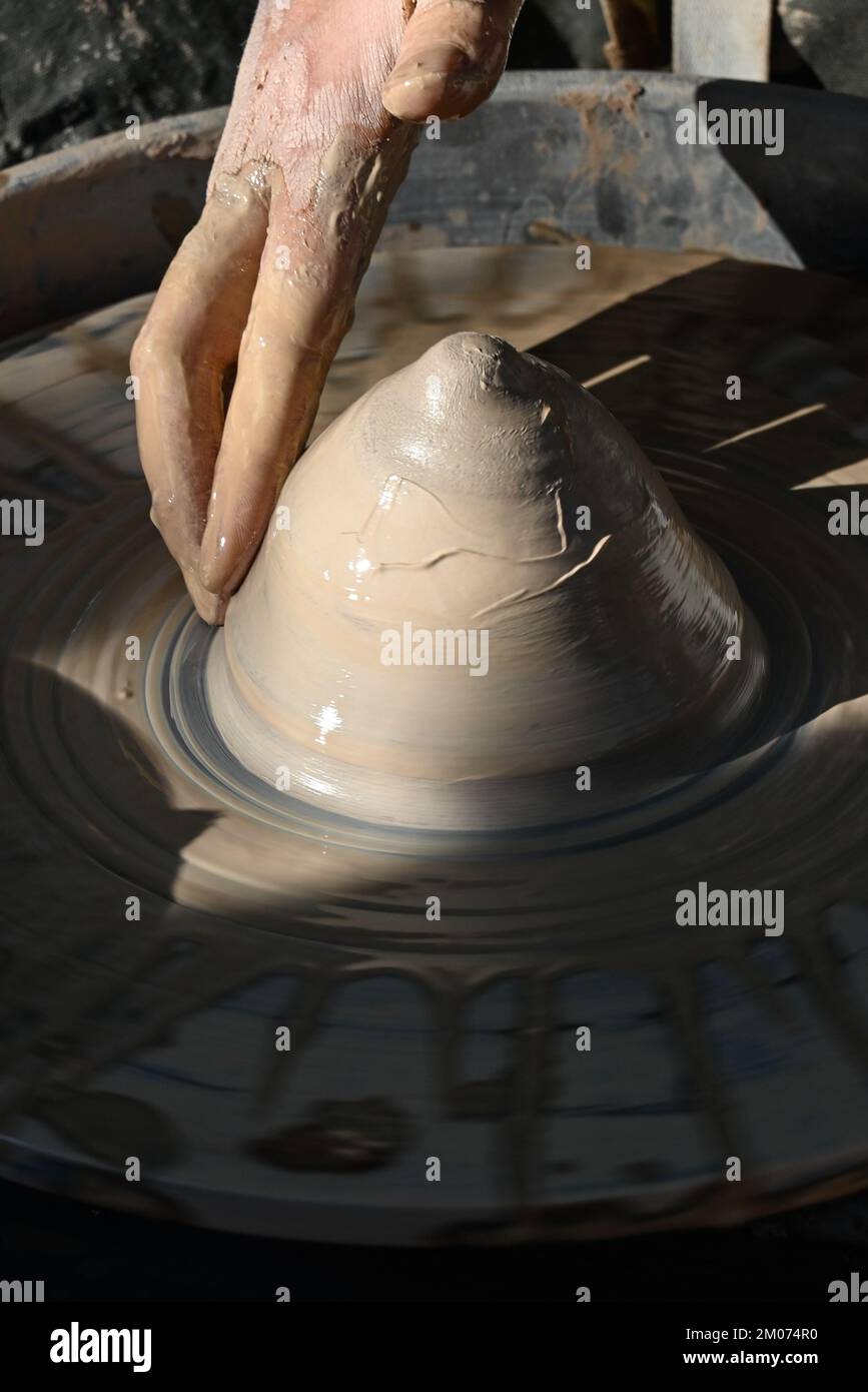 Primo piano di una mano bagnata che forma un cono di argilla in una ciotola su una ruota di ceramica in una dimostrazione alla fiera d'arte di Tucson, Arizona Foto Stock