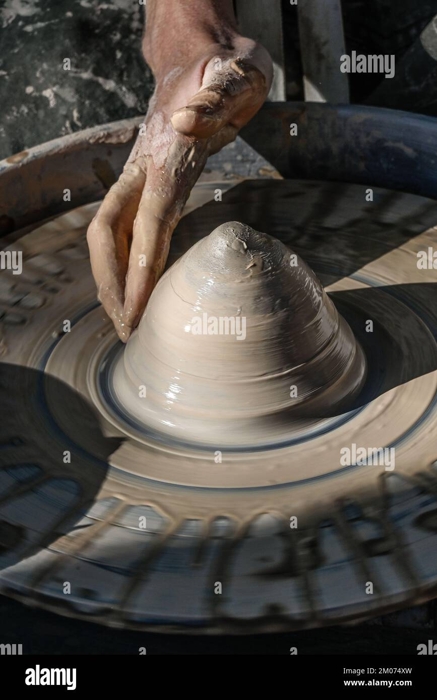 Primo piano di una mano bagnata che forma un cono di argilla in una ciotola su una ruota di ceramica in una dimostrazione alla fiera d'arte di Tucson, Arizona Foto Stock