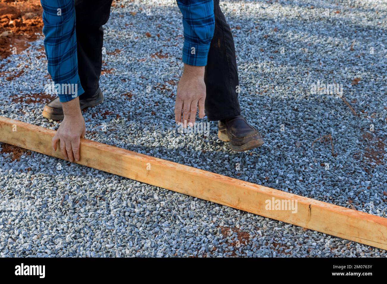 Livellamento di due per quattro legname di legno su ghiaia per fondazione ponte in capannone il cortile Foto Stock