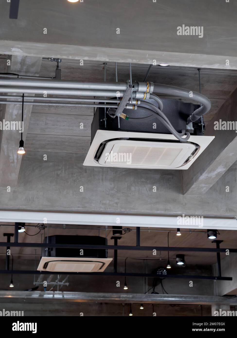 Decorazioni con aria condizionata a cassetta montate a soffitto vicino ai faretti dell'edificio in cemento, interni in stile loft. Tipo di soffitto Foto Stock