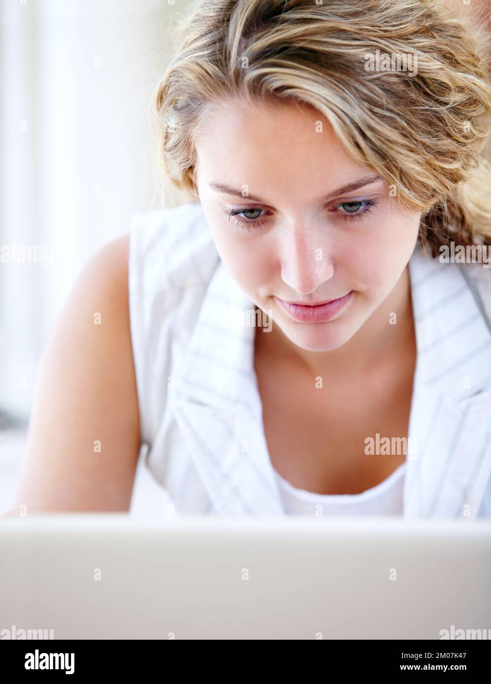 Perso nel web mondiale. Una giovane donna che naviga in Internet sul suo notebook mentre si sdraia sul pavimento. Foto Stock