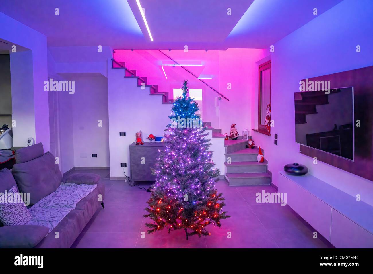 Bell'albero di Natale all'interno di una casa moderna con luci a strisce LED. Concetto di vacanza. Foto Stock