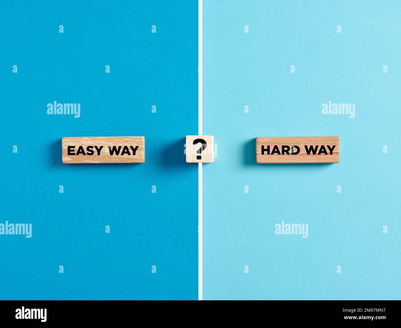 Le parole modo facile e modo duro su blocchi di legno con il simbolo del punto interrogativo. Dilemma o scelta fra scegliere il concetto facile o duro del senso. Foto Stock