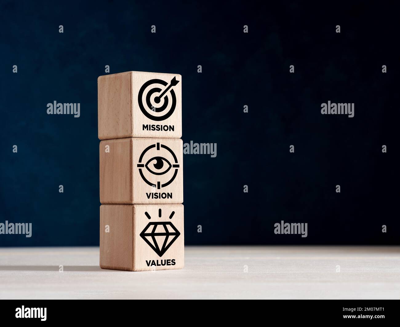 Missione, visione e valori di un'azienda. Cubi di legno impilati con simboli di missione, visione e valori aziendali. Foto Stock
