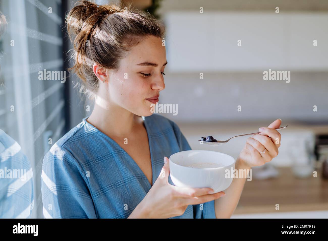 Giovane donna che ha muesli per la colazione in cucina, la routine mattutina e concetto di stile di vita sano. Foto Stock
