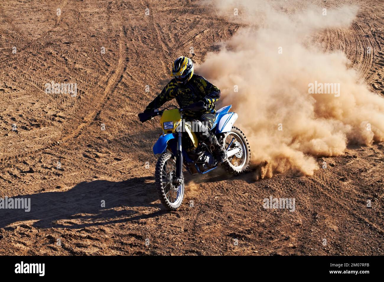 Lasciando i suoi concorrenti nella polvere. Un biker sterrato che corre lungo una pista con una nuvola di polvere che lo segue. Foto Stock