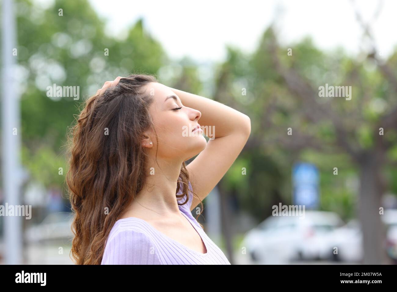 Profilo di una donna che respira i capelli toccanti nella strada Foto Stock