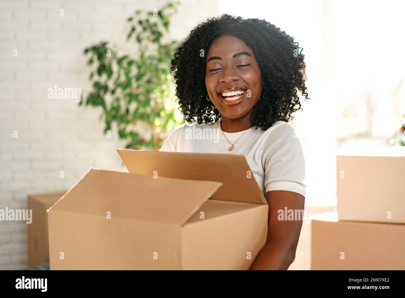 Felice giovane donna africana con scatola di cartone che si sposta in un nuovo posto Foto Stock