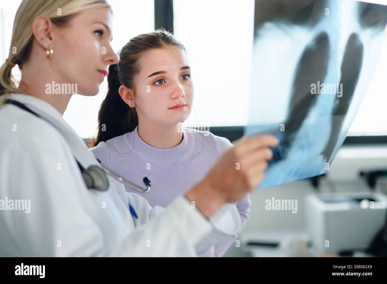 Medico giovane donna che mostra l'immagine radiografica dei polmoni alla sua paziente. Foto Stock