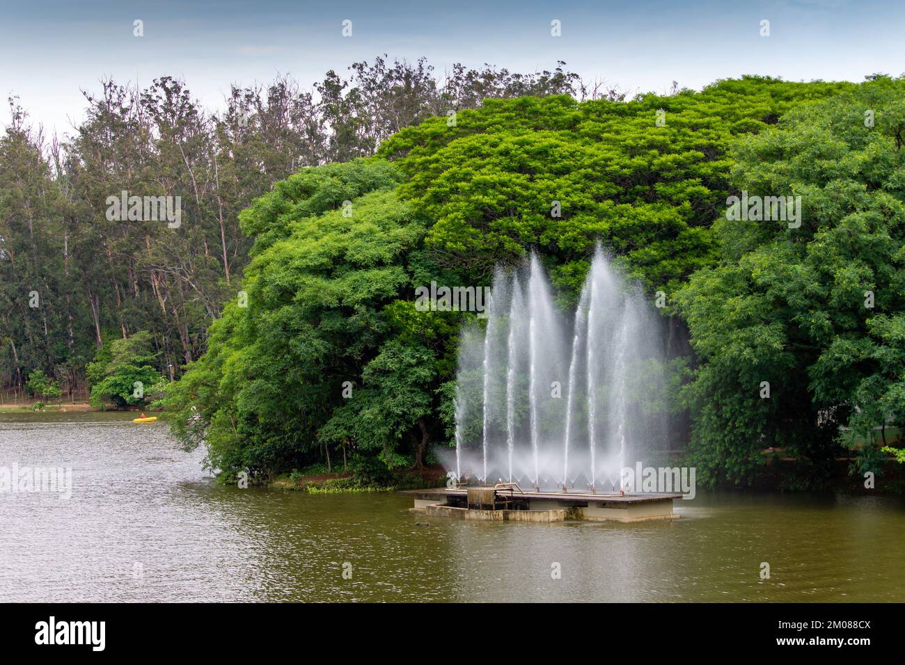 Una bella vista di una fontana su un fiume sullo sfondo di un albero denso Foto Stock