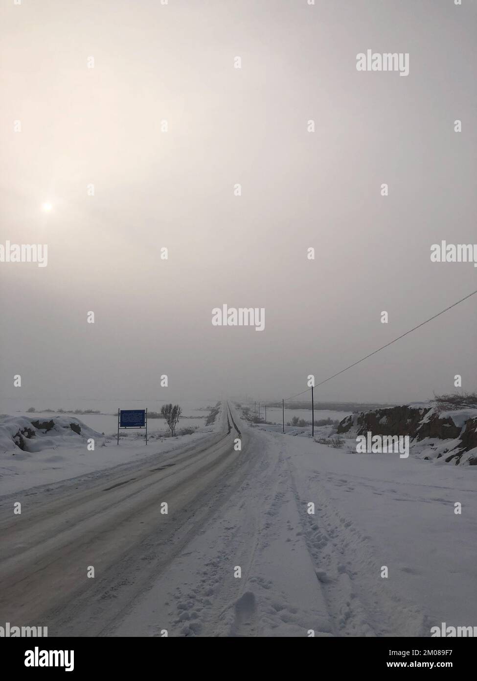 Un bellissimo scatto verticale di autostrada nel centro della valle coperta di neve sotto il cielo nebbia Foto Stock