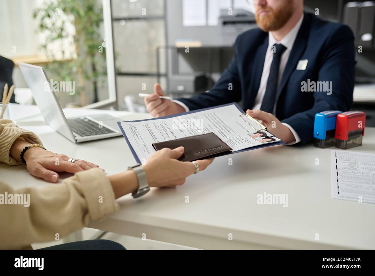 Primo piano di donne irriconoscibili che chiedono il visto nell'ufficio immigrazione degli Stati Uniti e che consegnano i documenti Foto Stock