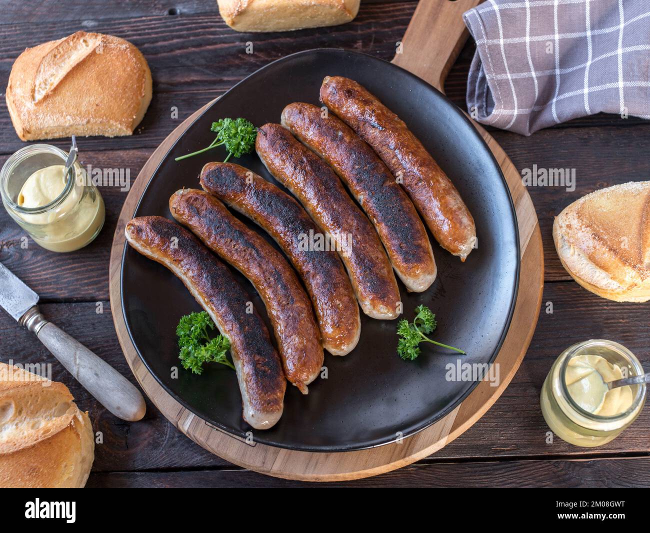 Salsiccia fritta con ciambelle e senape. Tradizionale pasto tedesco su tavolo di legno. Giacitura piatta Foto Stock