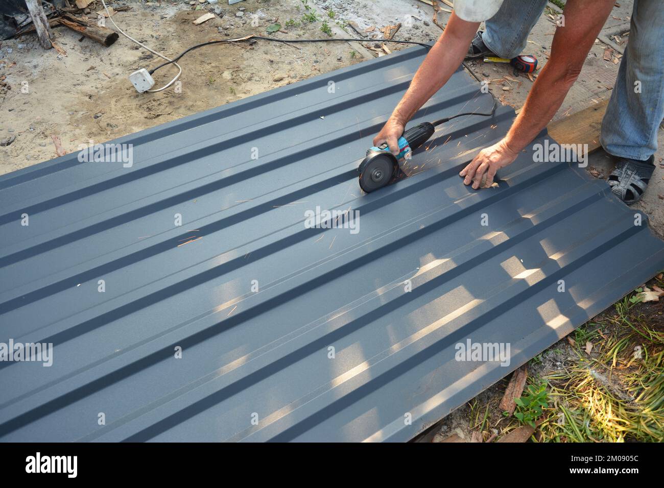 Carpentiere taglio lamiera leggera per tetti con rettificatrice. Costruzione di tetti. Foto Stock