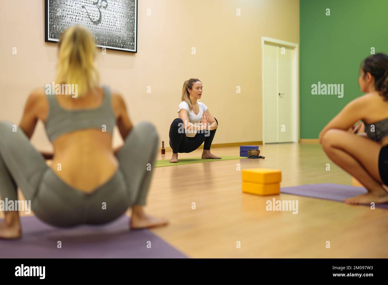 istruttore di yoga che si concentra sulla posa malasana in classe Foto Stock