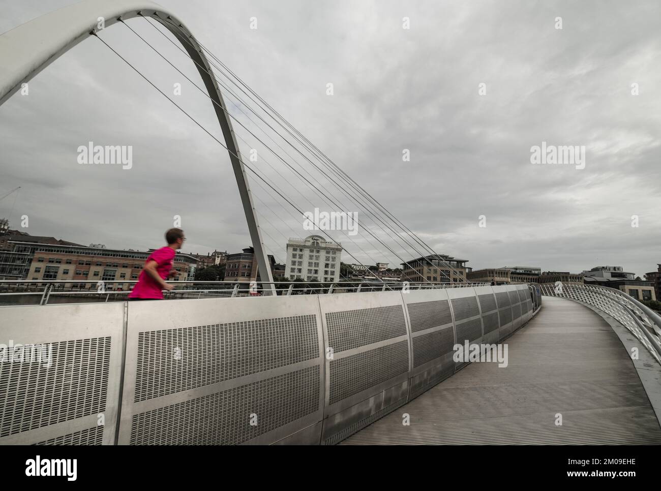 Jogger corre sopra il Millennium Bridge Gateshead con un gilet rosso brillante Foto Stock