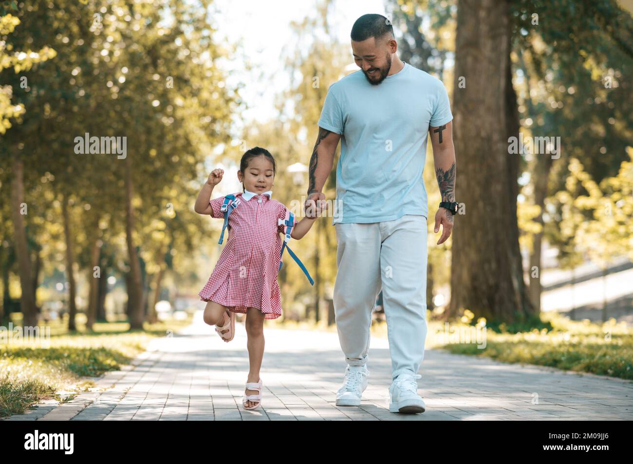 Papà e figlia che camminano nel parco mano in mano Foto Stock