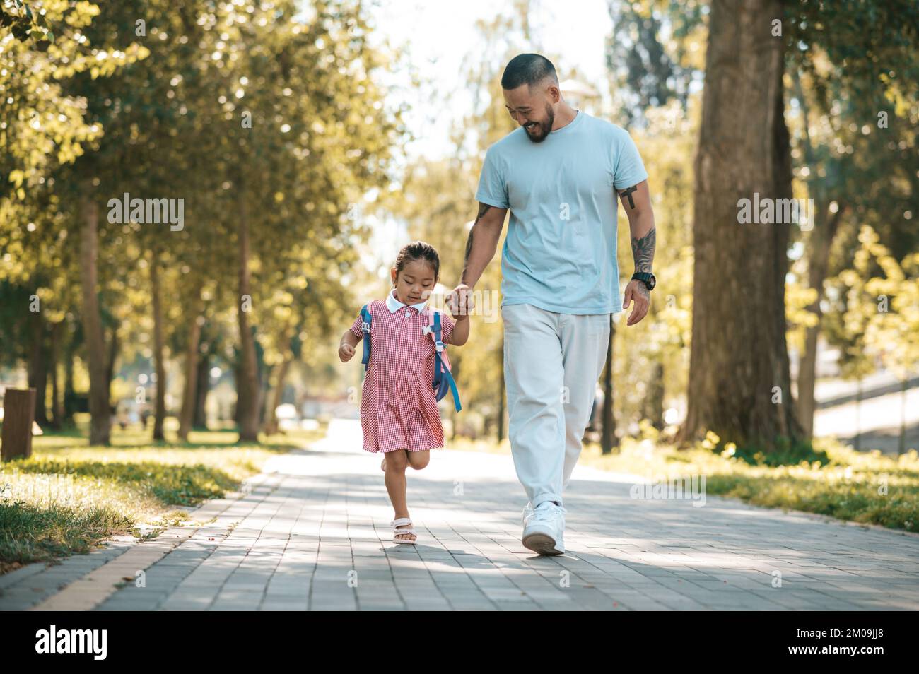 Papà e figlia che camminano nel parco mano in mano Foto Stock