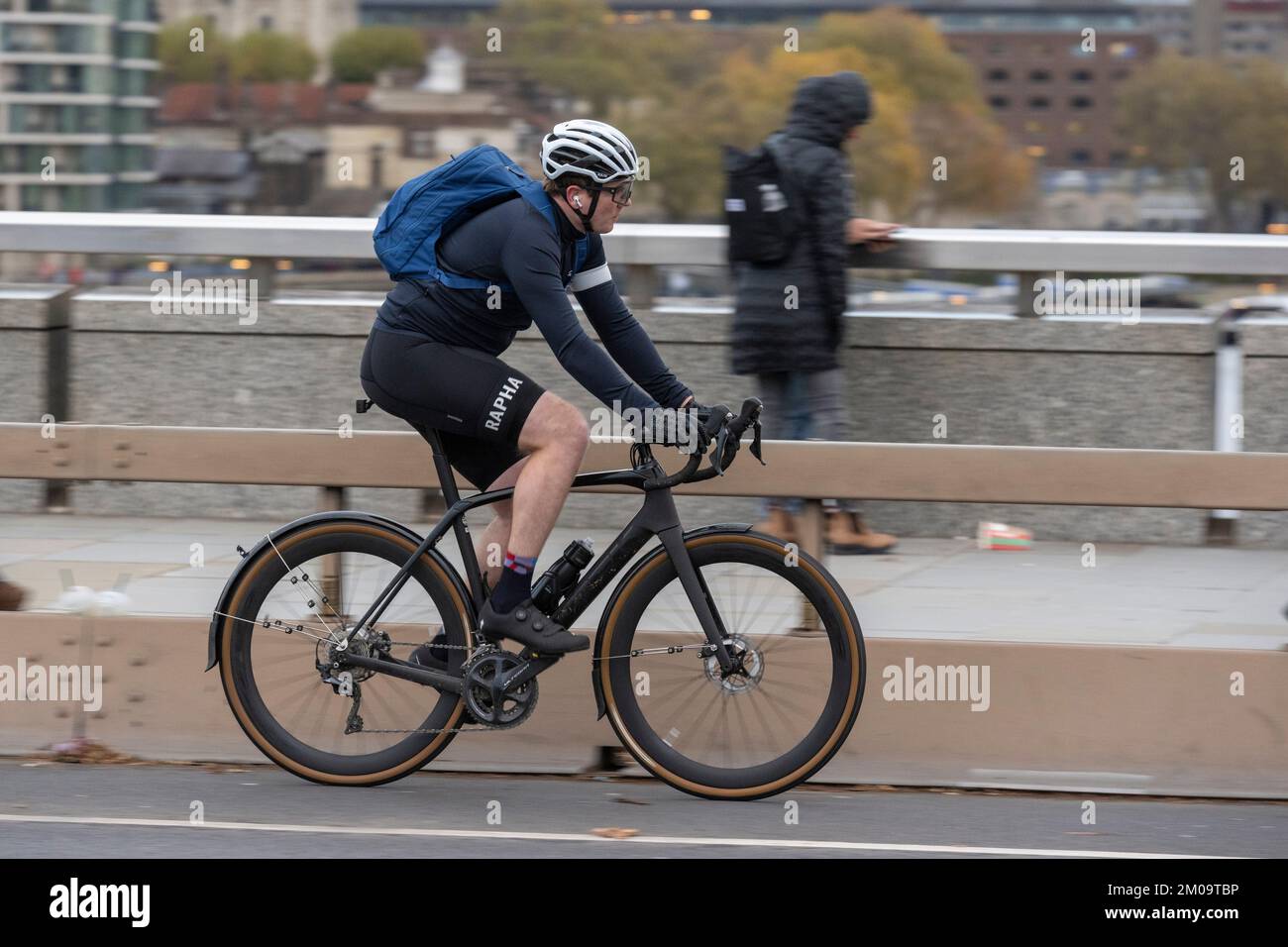 Un uomo che si collega in bicicletta durante l'ora di punta attraverso il London Bridge, Londra, Regno Unito. 18 Nov 2022 Foto Stock