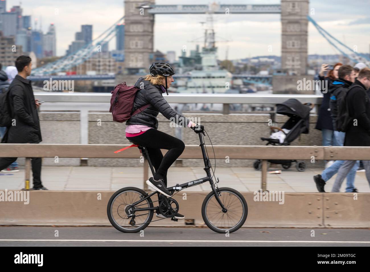 Una donna che si collega in bicicletta durante l'ora di punta attraverso il London Bridge, Londra, Regno Unito. 18 Nov 2022 Foto Stock
