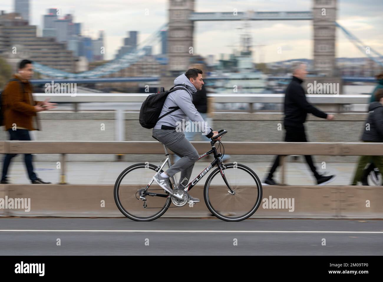 Un uomo che si collega in bicicletta durante l'ora di punta attraverso il London Bridge, Londra, Regno Unito. 18 Nov 2022 Foto Stock