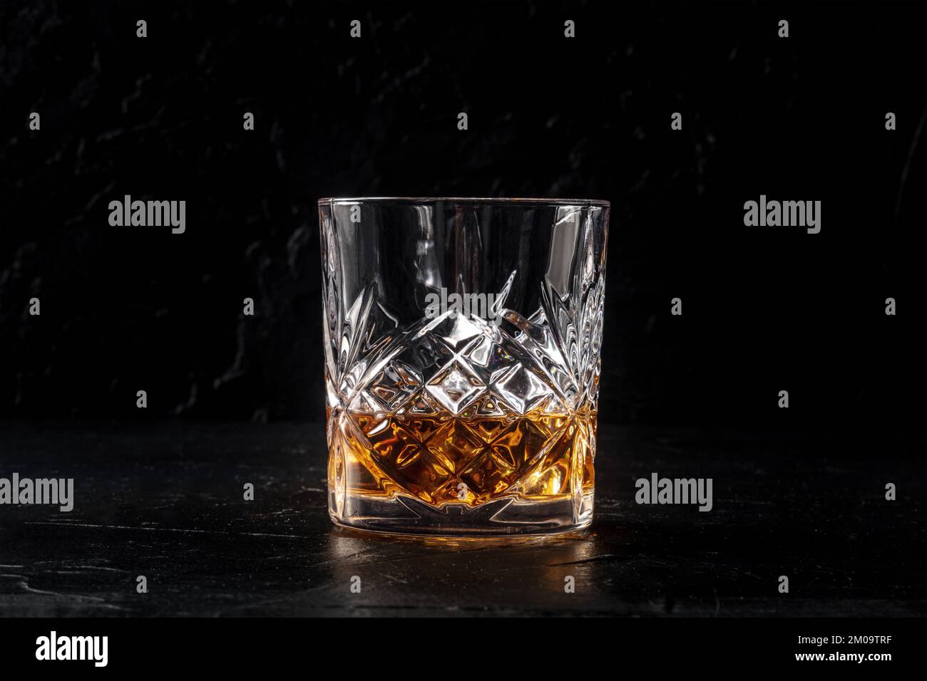 Whisky in un bicchiere di ghiaccio. Whisky borbonico sulle rocce su uno sfondo nero ardesia, una bevanda di lusso, con spazio copia Foto Stock