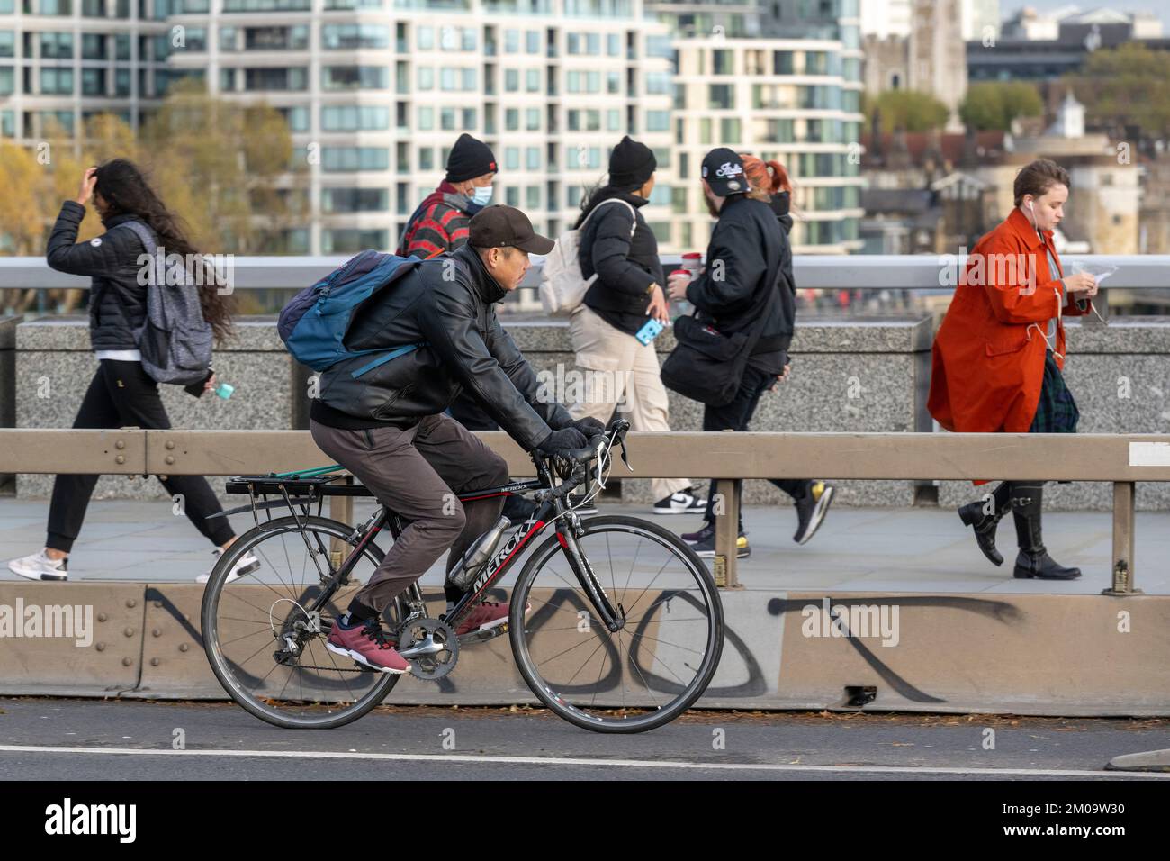 Un uomo che si collega in bicicletta durante l'ora di punta attraverso il London Bridge, Londra, Regno Unito. 17 Nov 2022 Foto Stock
