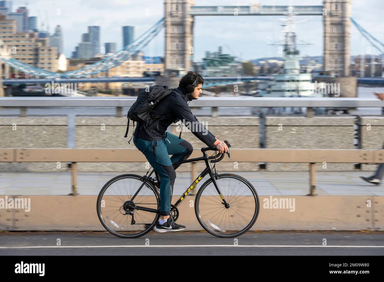 Un uomo che si collega in bicicletta durante l'ora di punta attraverso il London Bridge, Londra, Regno Unito. 17 Nov 2022 Foto Stock