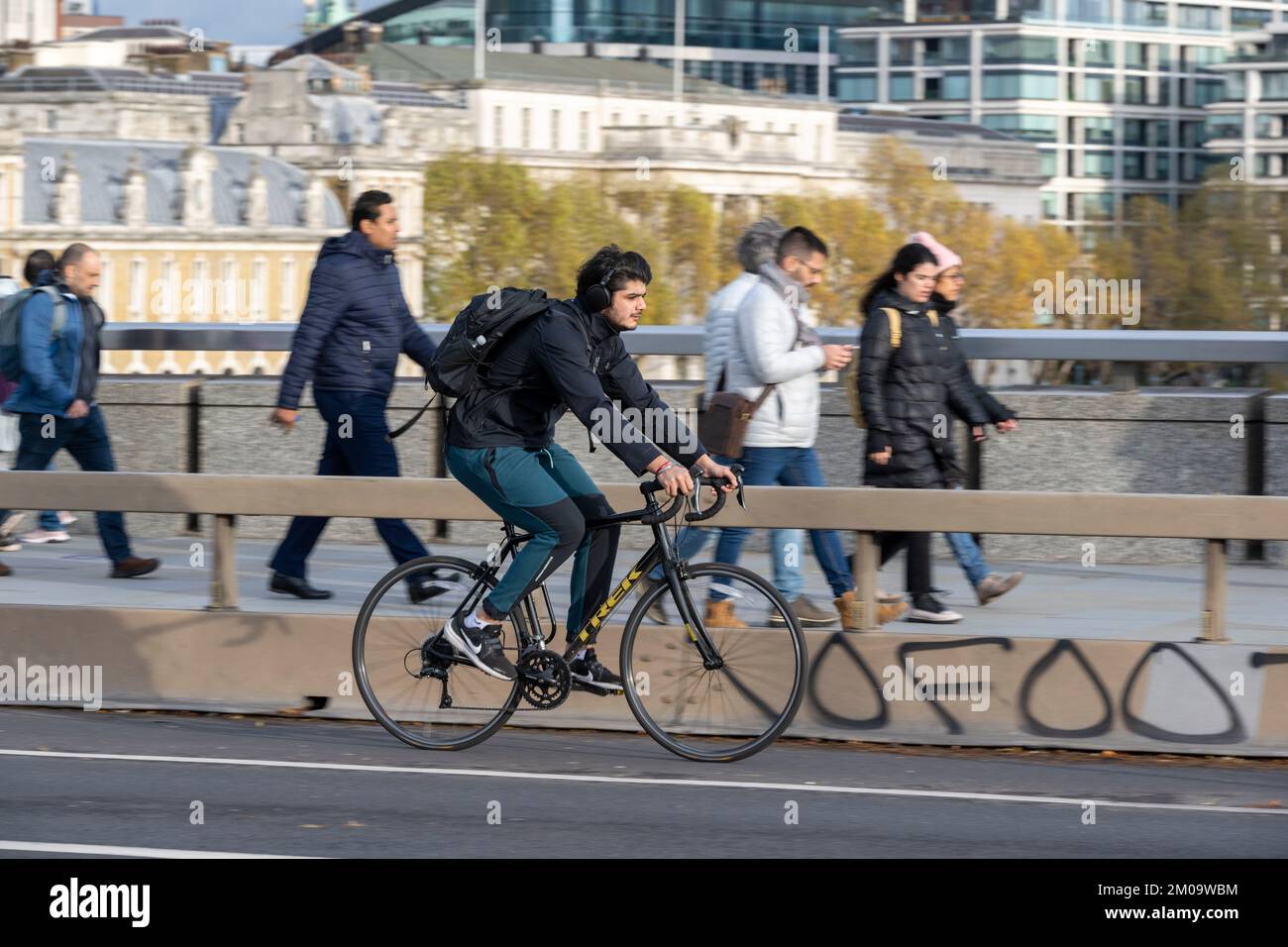Un uomo che si collega in bicicletta durante l'ora di punta attraverso il London Bridge, Londra, Regno Unito. 17 Nov 2022 Foto Stock