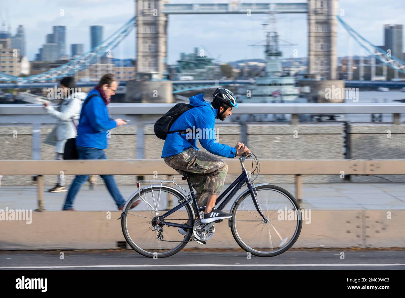 Un uomo che si collega in bicicletta durante l'ora di punta attraverso il London Bridge, Londra, Regno Unito. 17 Nov 2022 Foto Stock